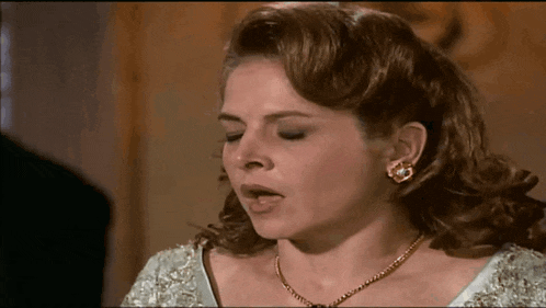 a woman wearing a necklace and earrings is making a face