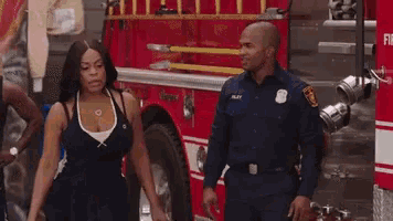 a man and a woman are walking in front of a fire truck