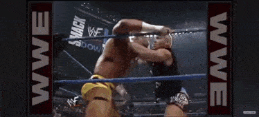 two men are wrestling in a wrestling ring and one of them is wearing a yellow shorts .