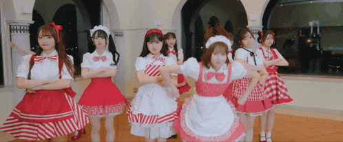 a group of girls dressed in maid outfits are dancing