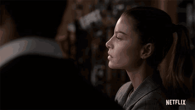 a woman in a ponytail is looking at a man in a suit with a netflix logo in the corner