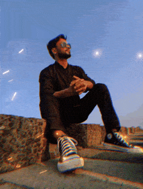 a man wearing sunglasses sits on some steps