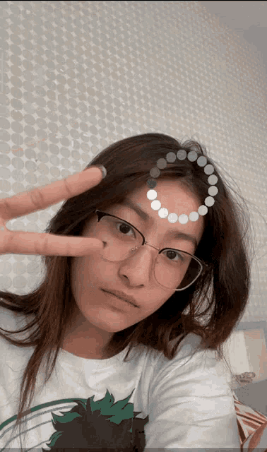 a woman wearing glasses and a white shirt is giving a peace sign