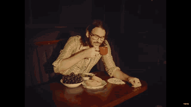 a man sits at a table with a cup of coffee and a plate of food