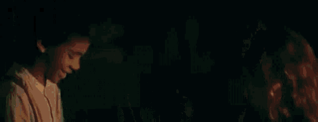 a boy and a girl are standing next to each other in a dark room holding hands .