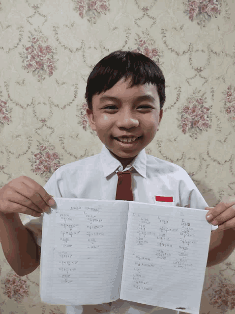 a boy in a white shirt and red tie is holding up a piece of paper with numbers on it