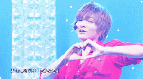 a man in a red shirt making a heart with his hands