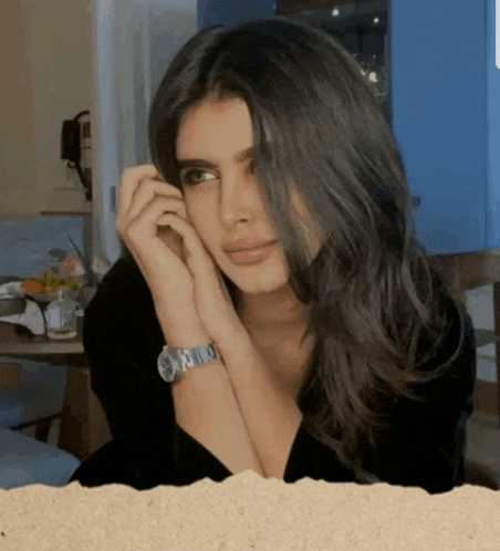 a woman wearing a black shirt and a watch looks at the camera