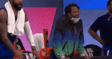 a man wearing a mask is sitting on a treadmill next to a basketball player .