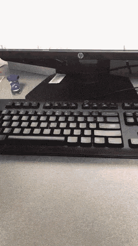 a black keyboard sits on a desk next to a hp computer