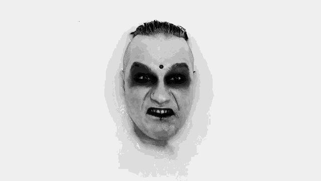 a black and white photo of a man 's face in a bathtub with black makeup .