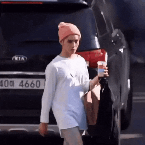 a man wearing a pink hat and a white shirt is holding a cup of coffee .