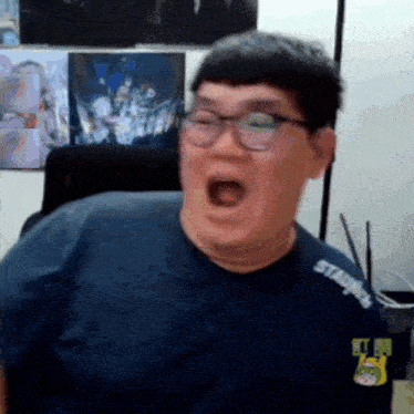 a man wearing glasses and a t-shirt that says stadium on it is making a funny face