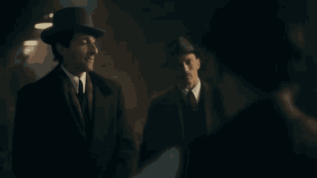 a man in a top hat stands next to another man in a suit