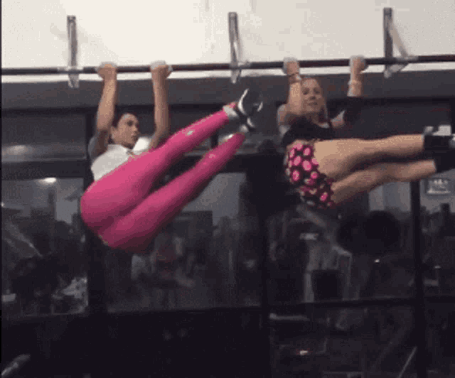 a woman in pink pants hangs upside down on a bar