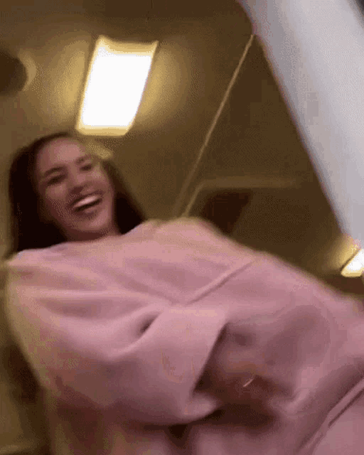 a woman wearing a pink sweater is laughing in a blurry photo