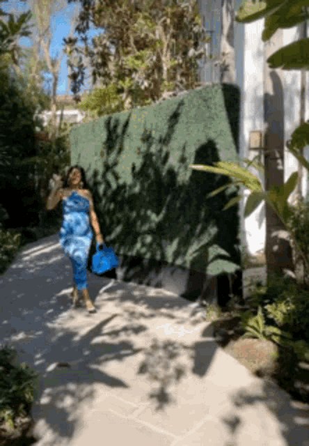 a woman in a blue dress walking down a sidewalk