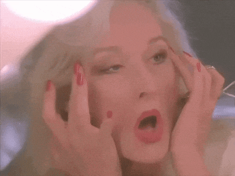 a woman with red nails is applying makeup to her face .