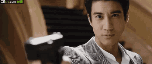 a man in a suit is looking at the camera with gifxiu.com written on the bottom right