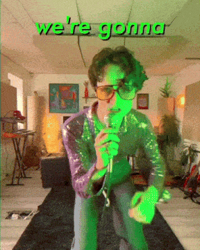a man singing into a microphone with the words " we 're gonna " behind him