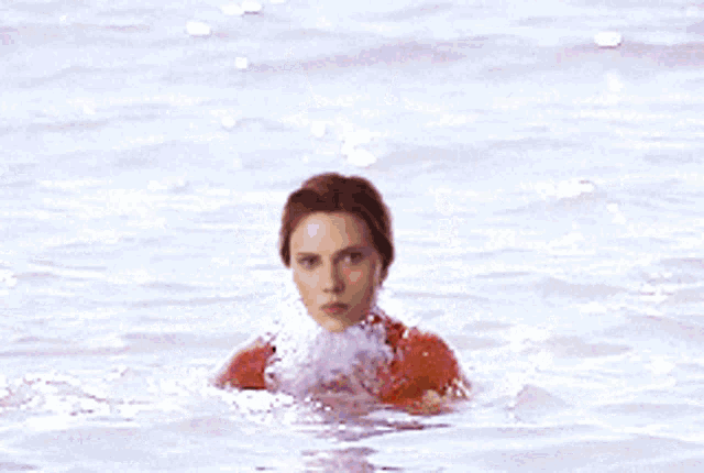 a woman in an orange bikini is standing in the water
