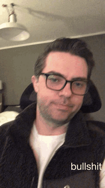 a man wearing glasses and a vest says bullshit on the bottom