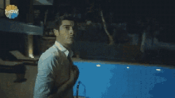 a man in a white shirt is standing in a living room with his shirt open .
