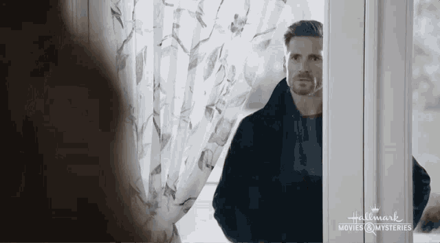 a man is standing in front of a window with a woman looking out .