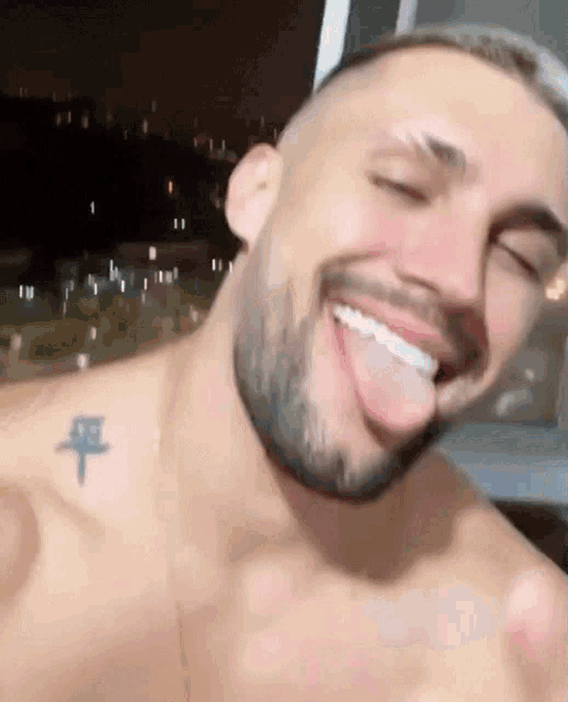 a shirtless man with a beard is sticking his tongue out .