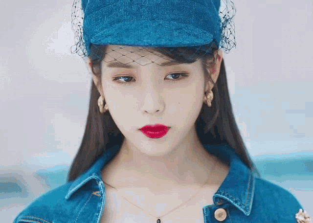 a close up of a woman wearing a hat and a denim jacket