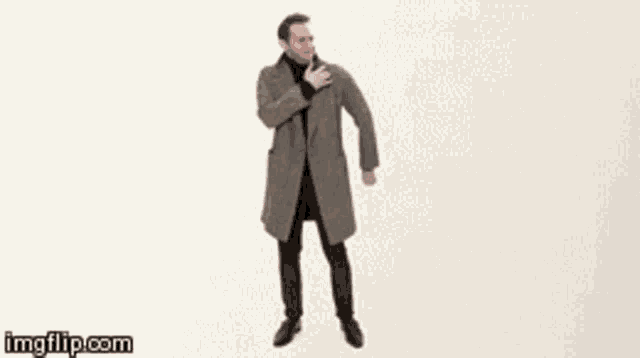 a man in a coat is standing with his hand on his chest
