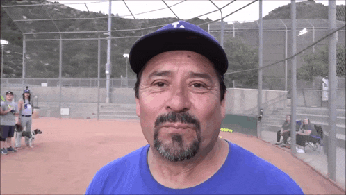 a man with a beard wearing a blue shirt and a la hat
