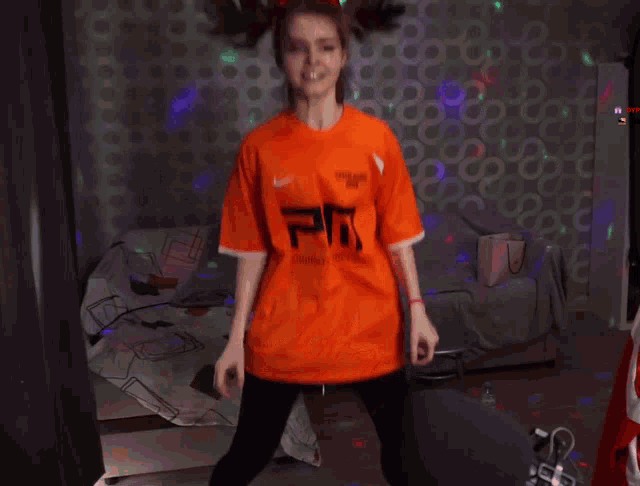 a girl wearing an orange shirt with the letter e on it