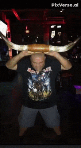 a man wearing a shirt that says iron maiden holds a large horn over his head