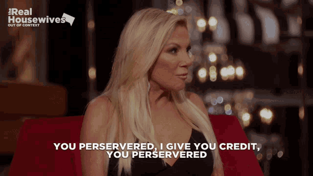 a woman is sitting on a red couch and says " you perservered i give you credit "