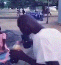 a man in a white shirt is drinking from a bottle on the street