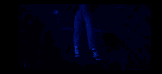 a close up of a woman 's face in a dark room with a blue light behind her .