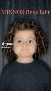 a little girl with curly hair is wearing a black shirt and smiling for the camera