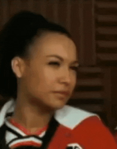 a close up of a woman 's face wearing a red and white cheerleading uniform .