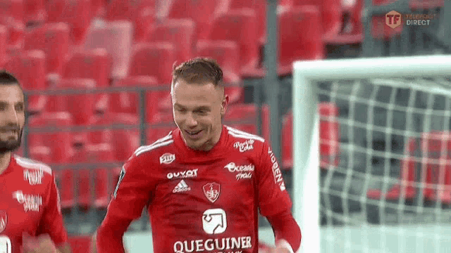 a soccer player wearing a red jersey with queguiner on it