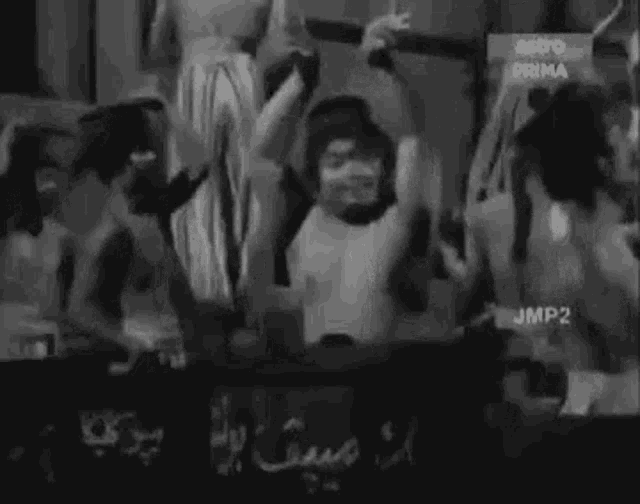 a black and white photo of a crowd of people dancing in a club .