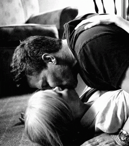 a man is kissing a woman on the floor in a black and white photo