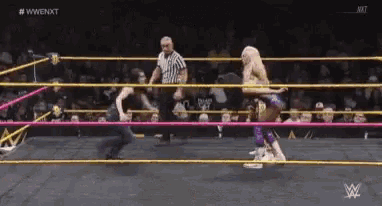 two women are wrestling in a wrestling ring with a referee watching