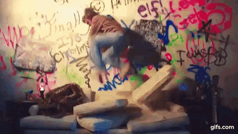 a person is sitting on a couch in front of a wall with graffiti on it