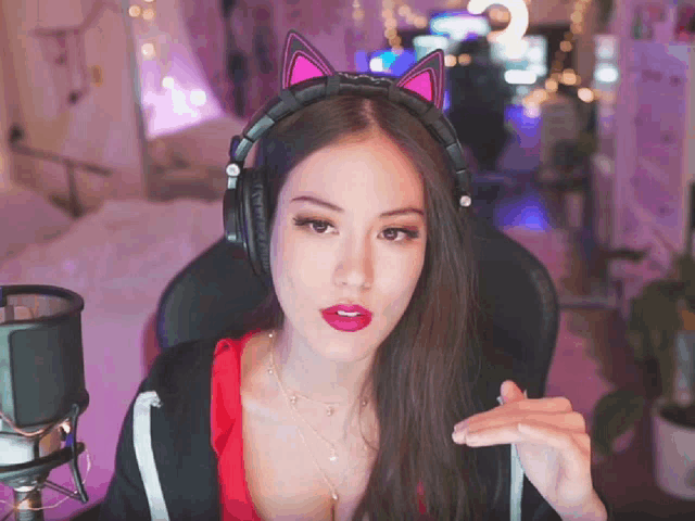 a woman wearing headphones with pink cat ears looks at the camera