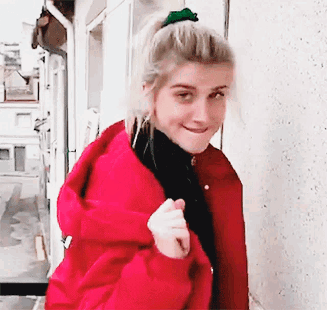 a woman wearing a red jacket and a green scrunchie on her hair