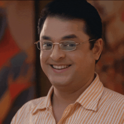 a man wearing glasses and an orange striped shirt smiles