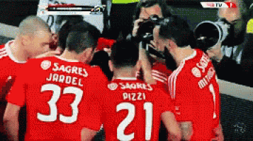 a group of soccer players wearing red jerseys with the numbers 33 and 21