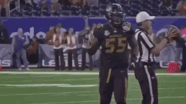 a football player is kneeling on the field while a referee talks to him .