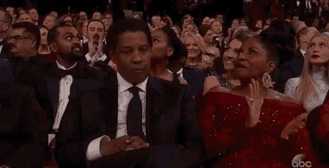 a man in a suit and tie is sitting in a crowd of people at an awards ceremony .